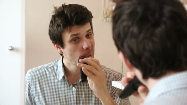 Macchina radere i peli del viso. Giovane uomo bello rasatura a secco con trimmer elettrico . — Video Stock