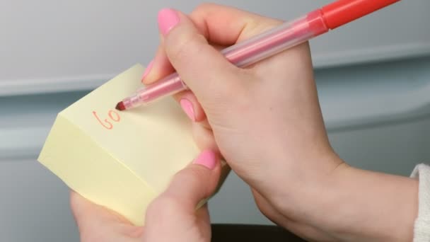 Primeros planos mujeres manos escribir en hojas de papel adhesivo amarillo palabras buena suerte y corazón de pintura . — Vídeos de Stock