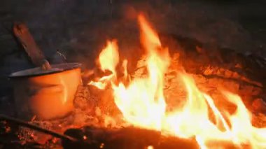Gıda şenlik bir tencerede pişirilir. Kömürlerin dalları ile çevirin. Yakın çekim.
