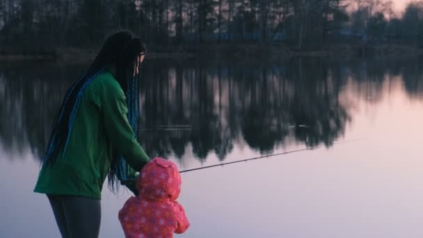 Mãe e filha de pesca no lago ao pôr do sol à noite . — Vídeo de Stock