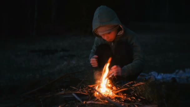 Niño de siete años enciende un fuego en el bosque . — Vídeo de stock