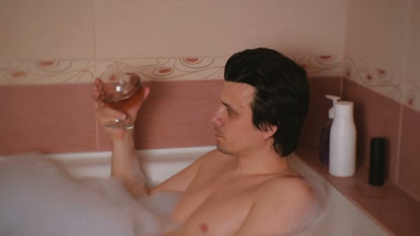 Le jeune homme prend un bain et boit du whisky. Repos et détente après le travail . — Video