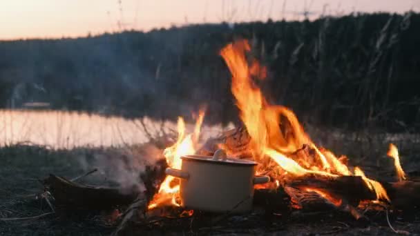 Das Essen wird am Lagerfeuer in einem Topf gekocht. Frauenhände berühren sich mit dem Topf. — Stockvideo