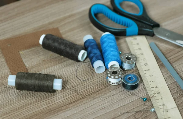 Sewing supplies scissors, thread, bobbins, pencil, a ruler on wooden table. — Stock Photo, Image
