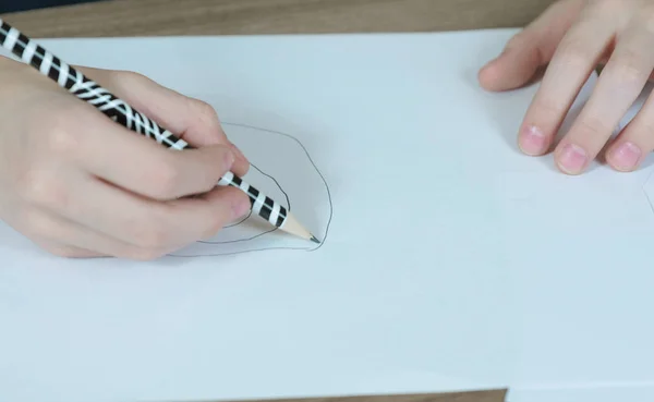 Крупным планом руки ребенка нарисованы простым карандашом на белой бумаге. Вид сверху . — стоковое фото