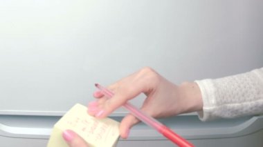 Closeup womans eller sarı etiket kağıt sayfalarının kelimelerle satın sopa: süt, ekmek, tavuk. Aile Not.