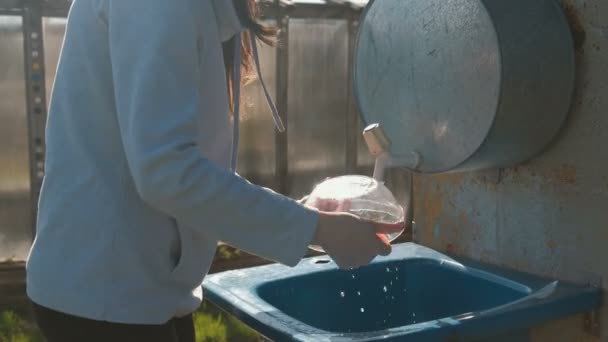 Woman washes a bowl in a rustic homemade sink outdoor. Hands close-up. — Stock Video