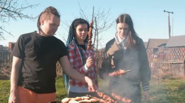 Grup Genç insanlar arkadaşlar Barbekü şaşlık et arka bahçesinde üzerinde kömür ızgara üzerine. Konuşmak ve birlikte gülümseyen.