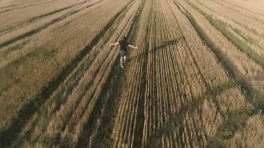 Uzanmış silah sahada koşan genç başarılı mutlu adam. Havadan panoramik görünümü. Arkadan görünüm.