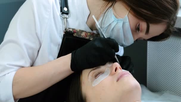 Kosmetikerin trennt die Wimpern mit einer Nadel und biegt sie zu Lockenwicklern. Peitschenkaminierung — Stockvideo