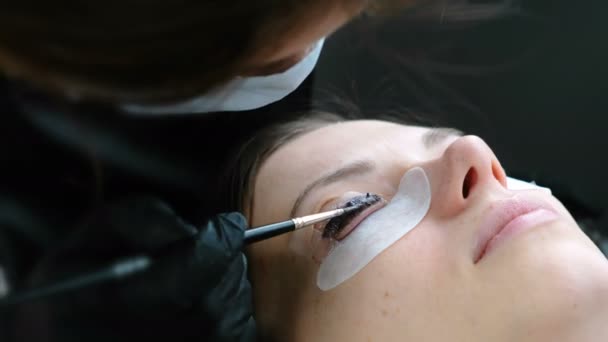 Θεραπεία ομορφιάς. Cosmetologist βάζει μαύρο χρώμα στις βλεφαρίδες. Πολυστρωμάτωση βλεφαρίδες. Closeup όψη πλάγια όψη. — Αρχείο Βίντεο