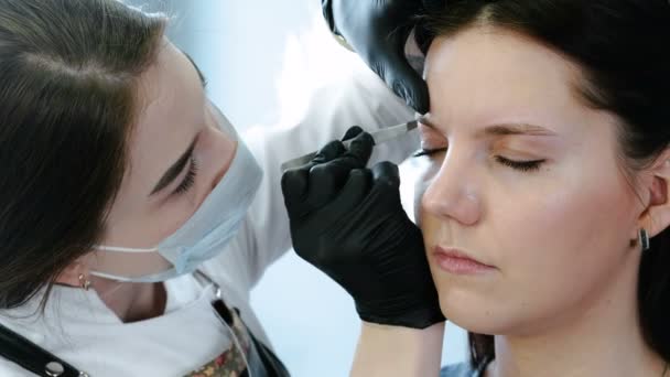 Kosmetolog utför förfarandet för korrigering ögonbryn med pincett. Främre närbild Visa — Stockvideo