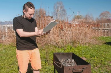 Genç adam bir kesme tahtası ile ızgara mangal kömürleri açılırsa.