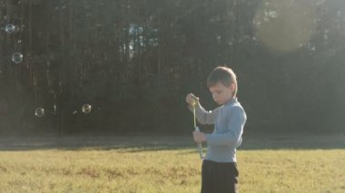 Çocuk sabun köpüğü forest yakınındaki bir çayırda bir sıcak bahar gününde sağlar..
