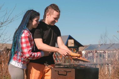 Erkek ve kadın genç çift pirzola Kavurma ve hamburger ızgara ekmek. Kapalı aile günü