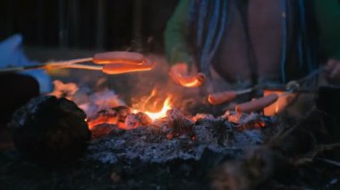 İnsanlar geceleri ormanda bir yangın sosis fry. Yakın çekim yakışıklı.