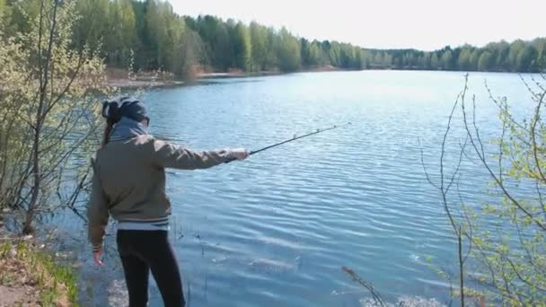 Femme pêche sur l'étang par une chaude journée de printemps . — Video
