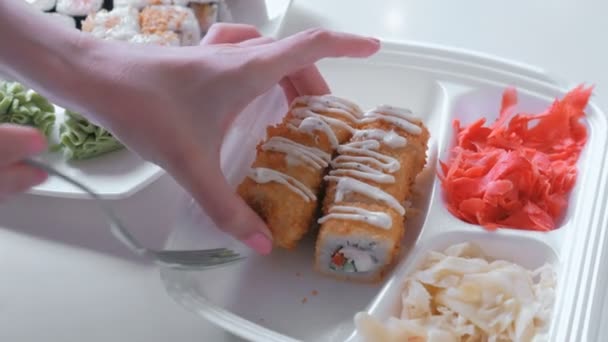 La donna mette rotoli e wasabi da imballaggio di plastica in un piatto. Mani in primo piano . — Video Stock