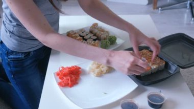 Kadın bir tabak içinde plastik ambalaj rulo ve wasabi koyar. Yakın çekim yakışıklı.
