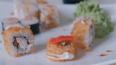 Zencefil giy kadın beyaz bir plaka üzerinde rulo ve yemek çubukları ile götürün. Yakın çekim el görünümü.