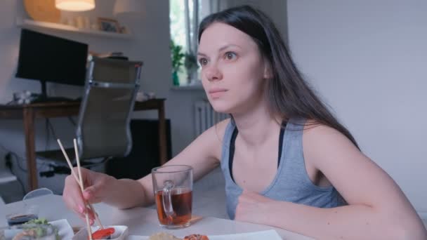 Junge Frau isst zu Hause Brötchen mit Holzstäbchen. — Stockvideo