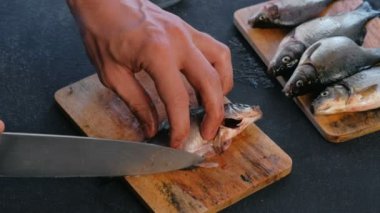 Adam balık sazan yüzgeçleri keser. Balık pişirme. Eller yakın çekim