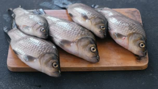 魚を調理します。木製基板のクローズ アップのテーブルに新鮮な小さな鯉. — ストック動画