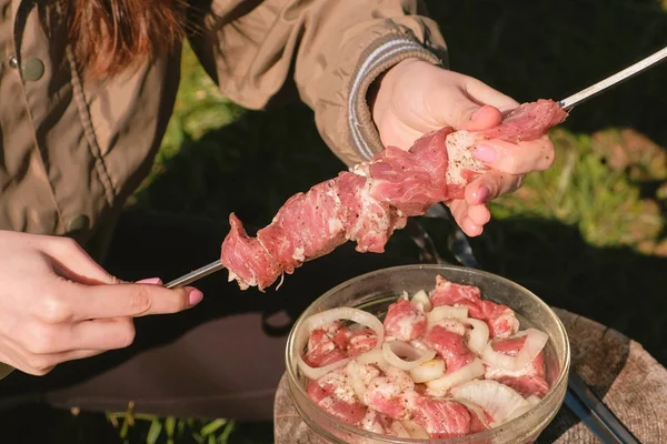 若い女性は、串に肉を置きます。クローズ アップ手。豚肉の串を料理. — ストック写真