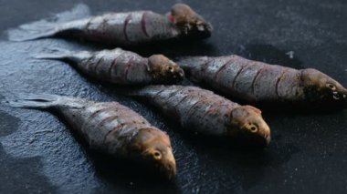 Adam bir sazan balık siyah masada tuz. Balık pişirme. El yakın çekim.