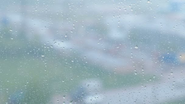 Raindrops flow down the window close-up. View of sity and road from wet window, blur — Stock Video