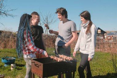 Grup Genç insanlar arkadaşlar Barbekü şaşlık et arka bahçesinde üzerinde kömür ızgara üzerine. Konuşmak ve birlikte gülümseyen.