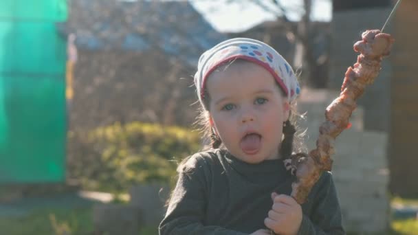 Маленькая милая девочка ест шашлык для барбекю на шампуре . — стоковое видео