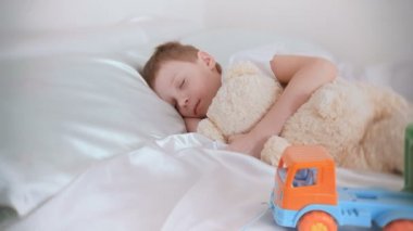 Onun oyuncak ayı ve plastik araba ile uyku 7 yaş çocuk.