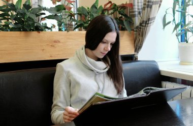 Hafif bir ceket esmer genç kadın bir kafede oturan menü okur