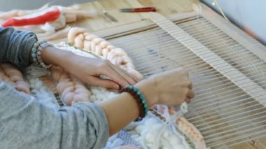 Tezgâh üzerinde dokuma. Kadının eller tezgâh üzerinde çalışan manikür olmadan. Yan görünümü. Çerçeve ipliklerini iğne threading.