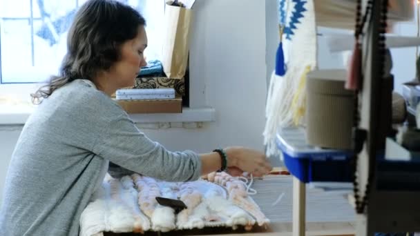 Weaving on a loom. Woman runs the yarn through the threads of the loom with her hands. — Stock Video