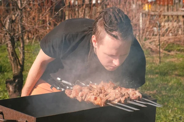 Молоді чоловіки з жахом на волоссі готують м'ясо шашлика на деревному грилі на задньому дворі . — стокове фото