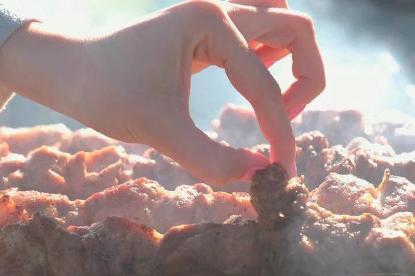 女性の涙の炭火の上に串で焼いた肉豚肉バーベキューの作品。肉と梨花の手のクローズ アップ. — ストック写真