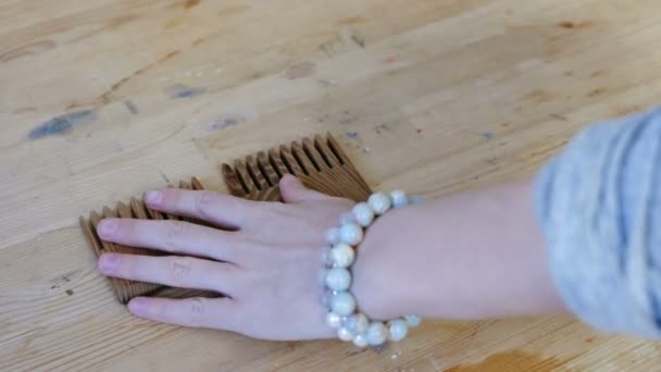 Weaver atölyede ahşap bir masa tarak koyar. Kadın el closeup elleri üzerinde boncuk bilezik ile — Stok video