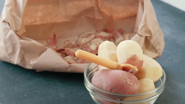 Batatas em uma tigela. Batatas descascadas. Limpeza em um saco ecológico no fundo . — Vídeo de Stock
