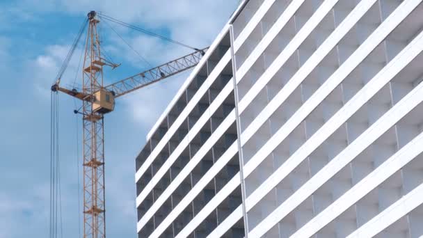 Construcción de un edificio de varios pisos. Casa y grúa de construcción en el fondo del cielo . — Vídeo de stock