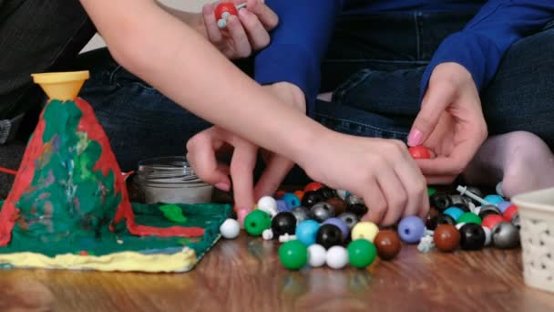 Closeup hands of mom and son building molecule models of colored plastic construction set. — Stock Video