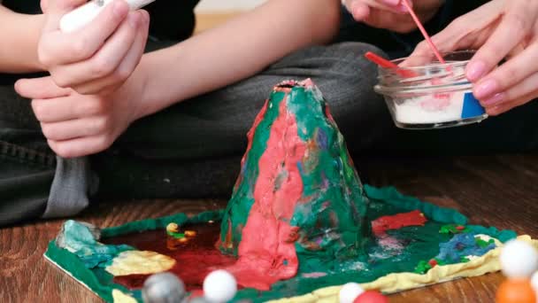 Mamá e hijo hacen experiencia con el volcán de plastilina hace erupciones de espuma en casa. Reacción química con emisión de gases . — Vídeos de Stock