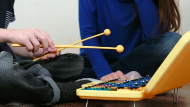Playing music instrument. Closeup boys hand playing on xylophone and his mom sitting near him. — Stock Video