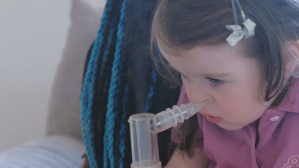 Το μικρό χαριτωμένο κορίτσι εισπνοή μέσω της συσκευής εισπνοής μάσκα με τη μαμά της. Χρησιμοποιούν νεφελοποιητή και συσκευή εισπνοής για τη θεραπεία. — Αρχείο Βίντεο