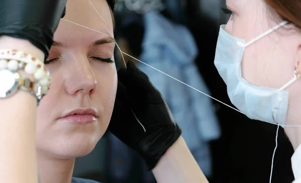 Косметолог проводит процедуру коррекции нанизывания брови. Вид сбоку . — стоковое фото