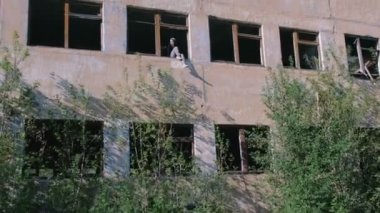 Birçok kırık camlar yok çok katlı binanın penceresindeki oturan kadın.