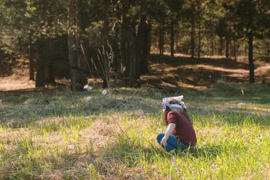 Küçük şirin kız ormanda yürür ve otların arasında oturur.