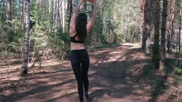 La mujer en ropa deportiva va al parque y se calienta antes de correr. Vista trasera . — Vídeos de Stock