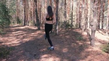 Kadın ormanda spor egzersizleri yapıyor. Ağır çekim.